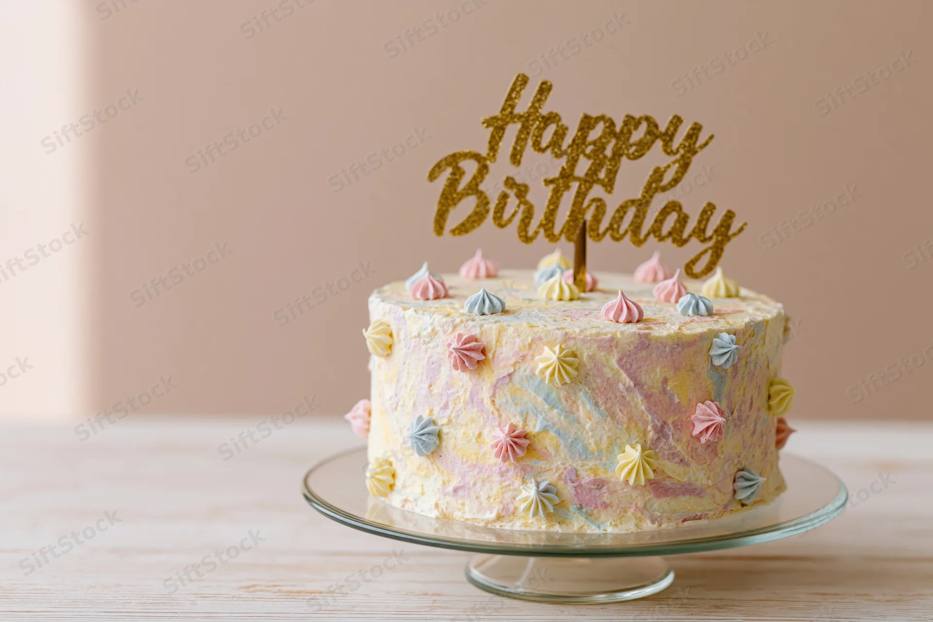 Decorated birthday cake with gold glitter topper on glass stand on wooden table