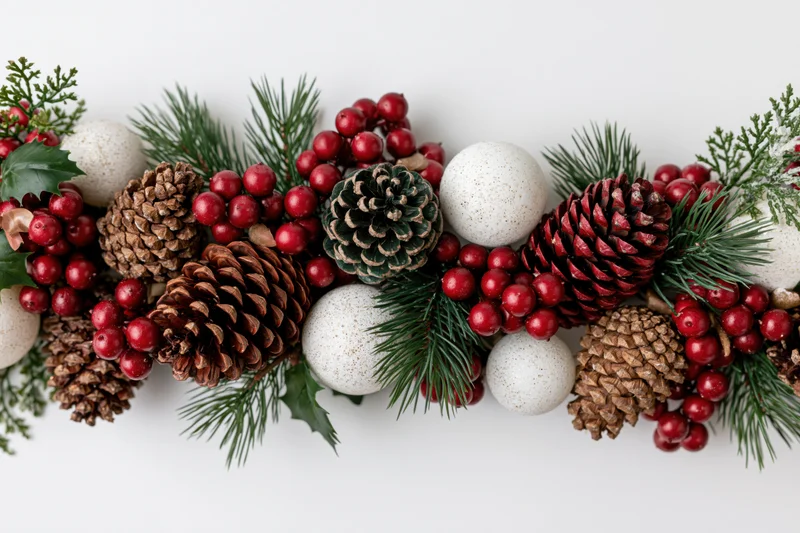 Horizontal christmas garland with pine cones red berries and white ornaments on white background