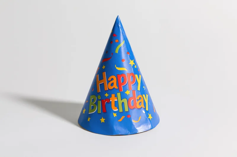 Blue paper birthday party hat standing upright on white surface