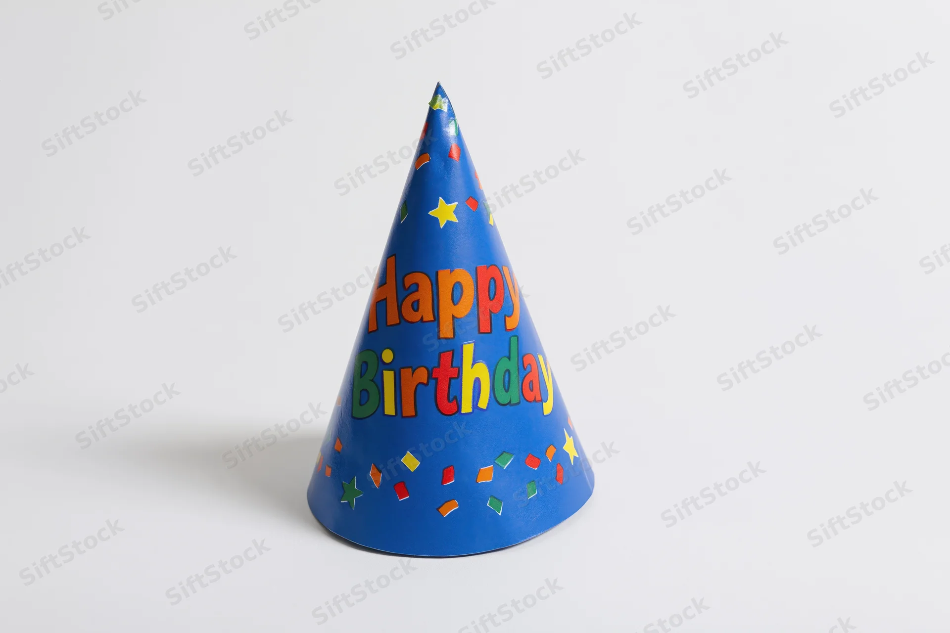 Blue paper birthday party hat with colorful stars and confetti standing upright on white background