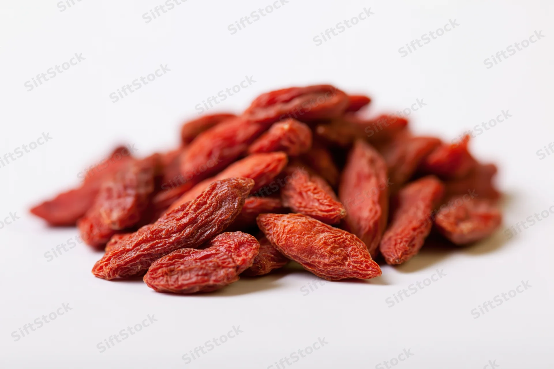 Pile of dried goji berries on white surface