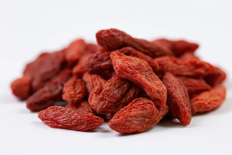 Pile of dried goji berries on white surface
