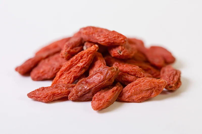 Dried goji berries piled loosely on a white surface
