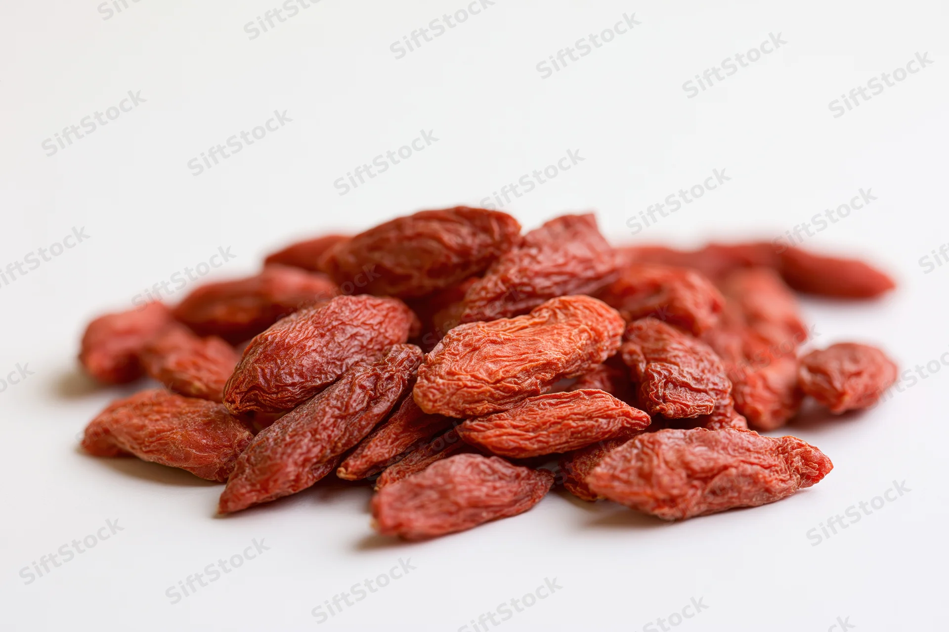 Dried goji berries piled loosely on a white surface