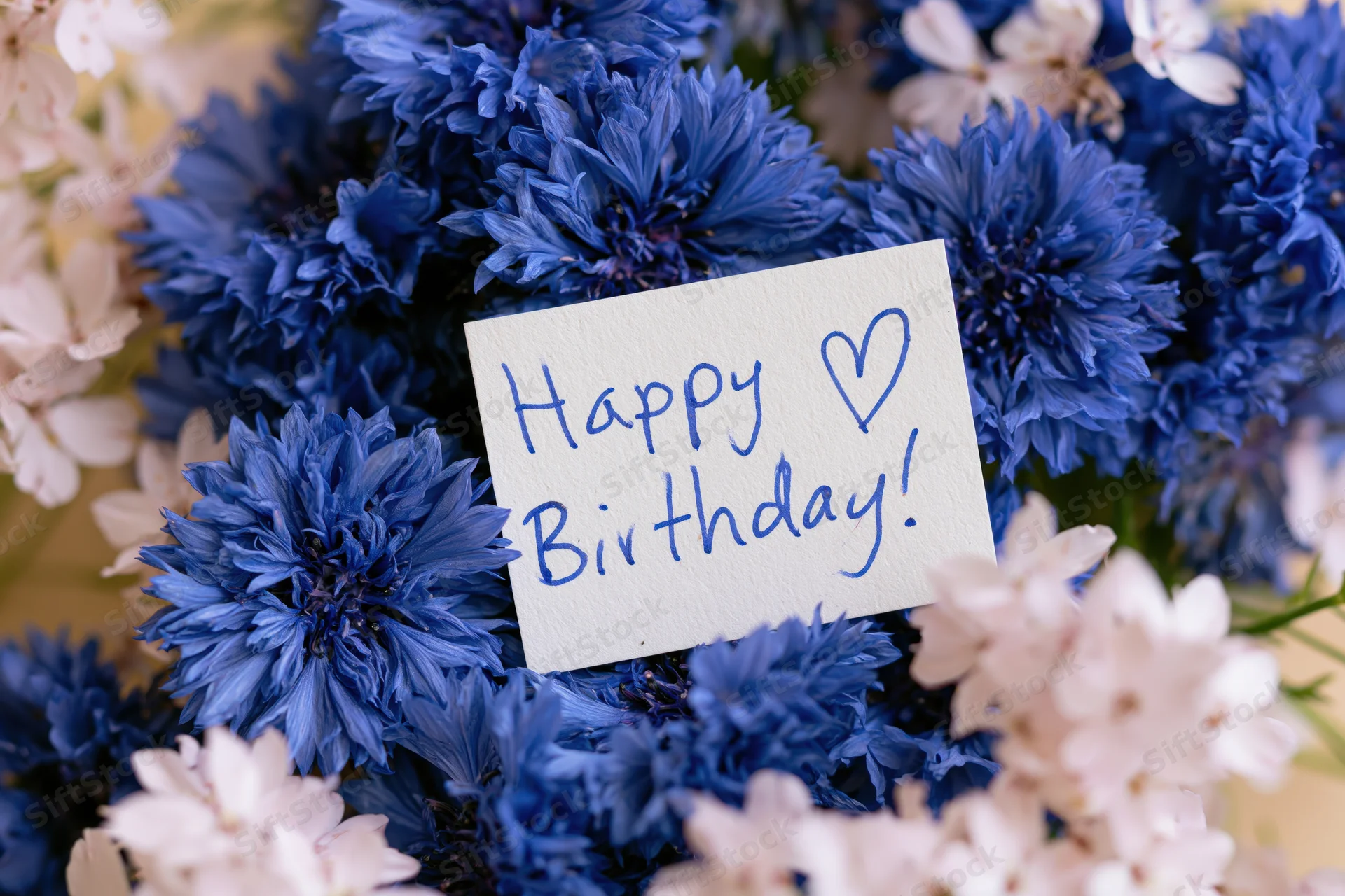 Blue and white flowers with a handwritten birthday card placed in the center