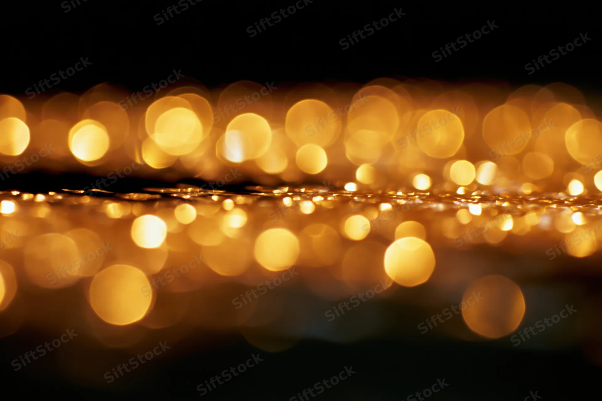 Abstract golden bokeh lights glowing softly against dark background with copyspace
