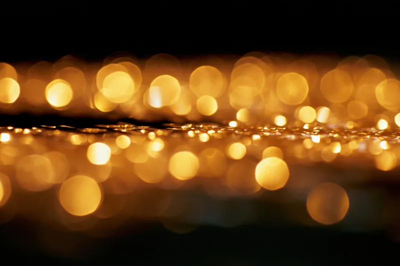 Abstract golden bokeh lights glowing softly against dark background with copyspace