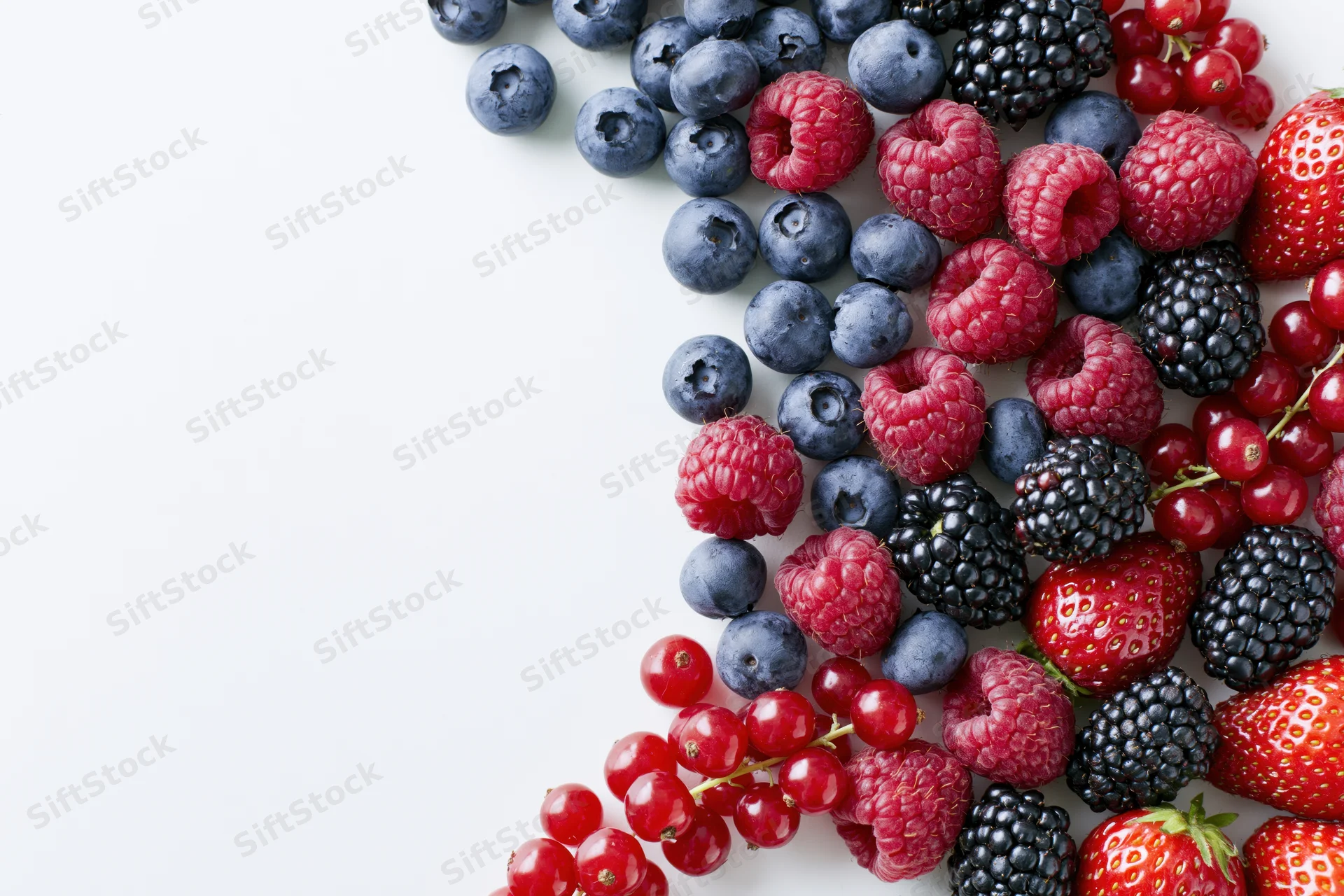 Assorted fresh berries arranged along the right edge on a white surface