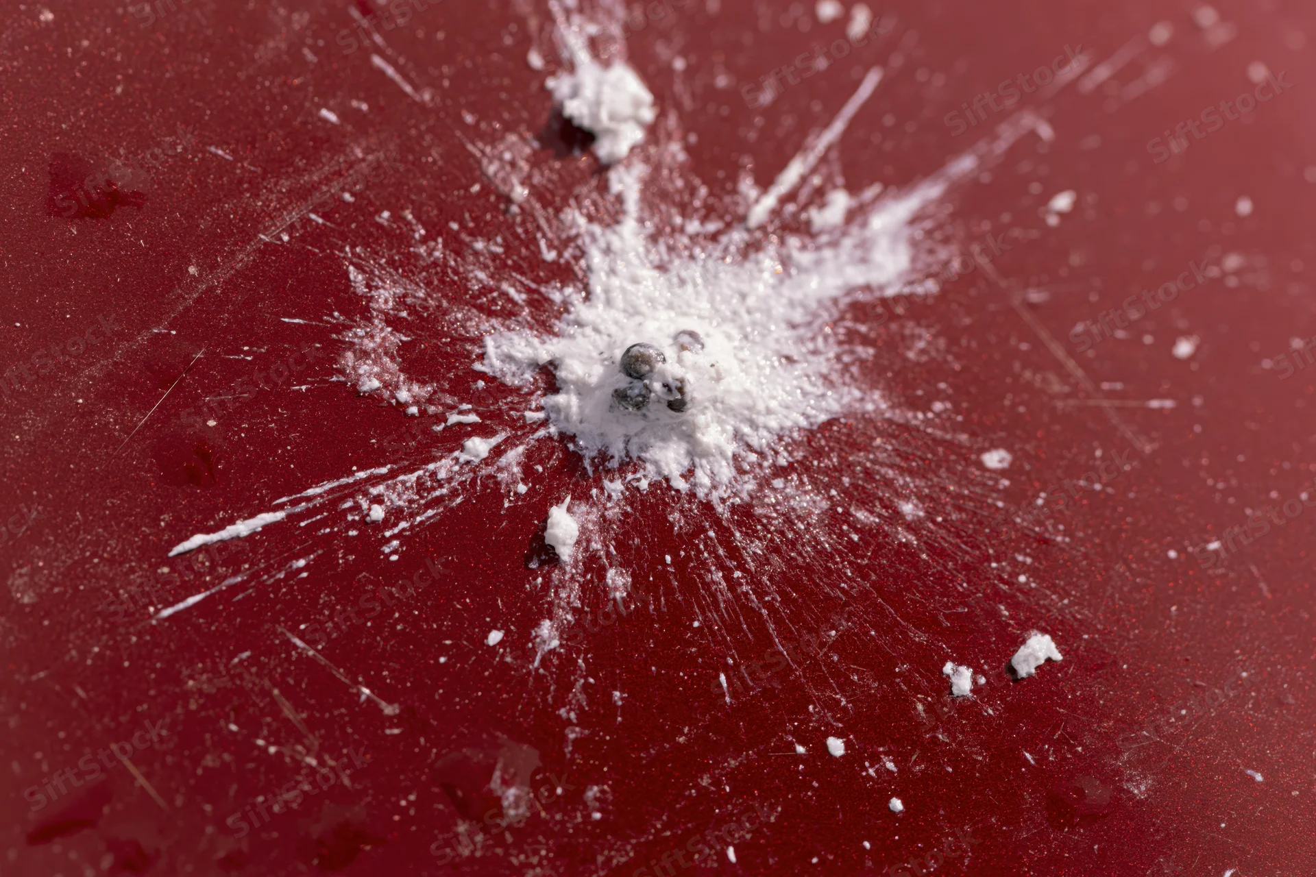 Bird dropping splattered on glossy red car surface