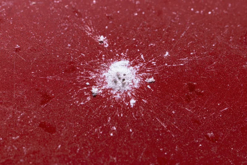 Bird dropping splattered on glossy red car surface
