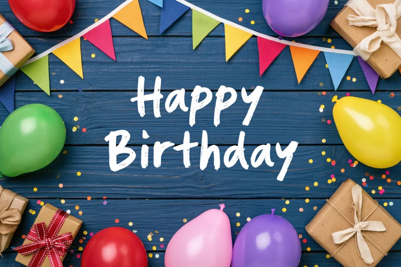 Colorful birthday party decorations with balloons, gifts and confetti on blue wooden table flat lay