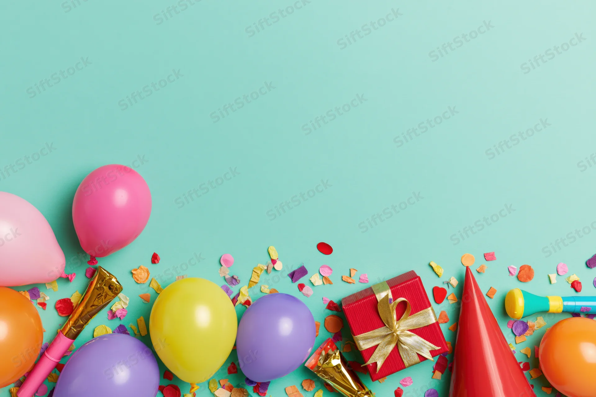 Birthday party supplies arranged along the bottom edge of a teal background with copyspace above