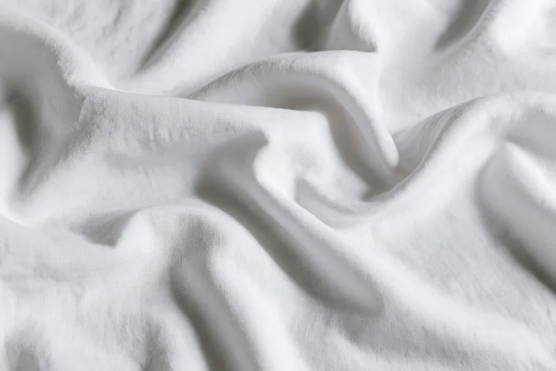 Crumpled white cotton bed sheet in close-up flat lay filling frame