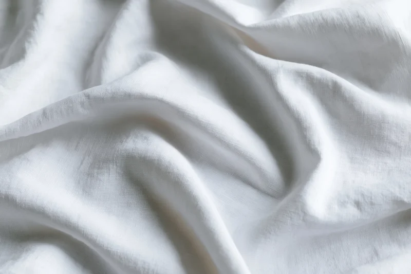 Crumpled white cotton bed sheet in close-up flat lay filling frame