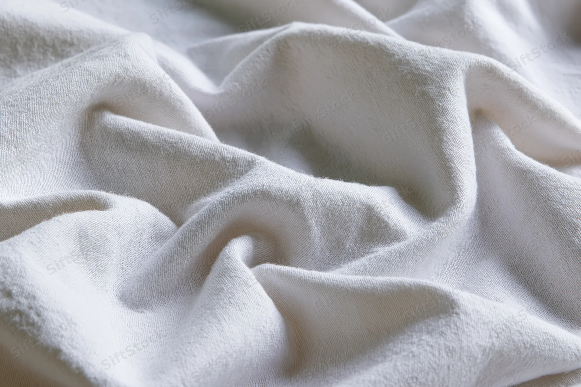 Crumpled white cotton fabric filling the frame with soft folds and natural texture