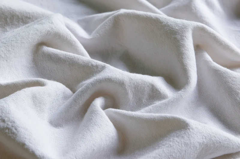 Crumpled white cotton fabric filling the frame with soft folds and natural texture