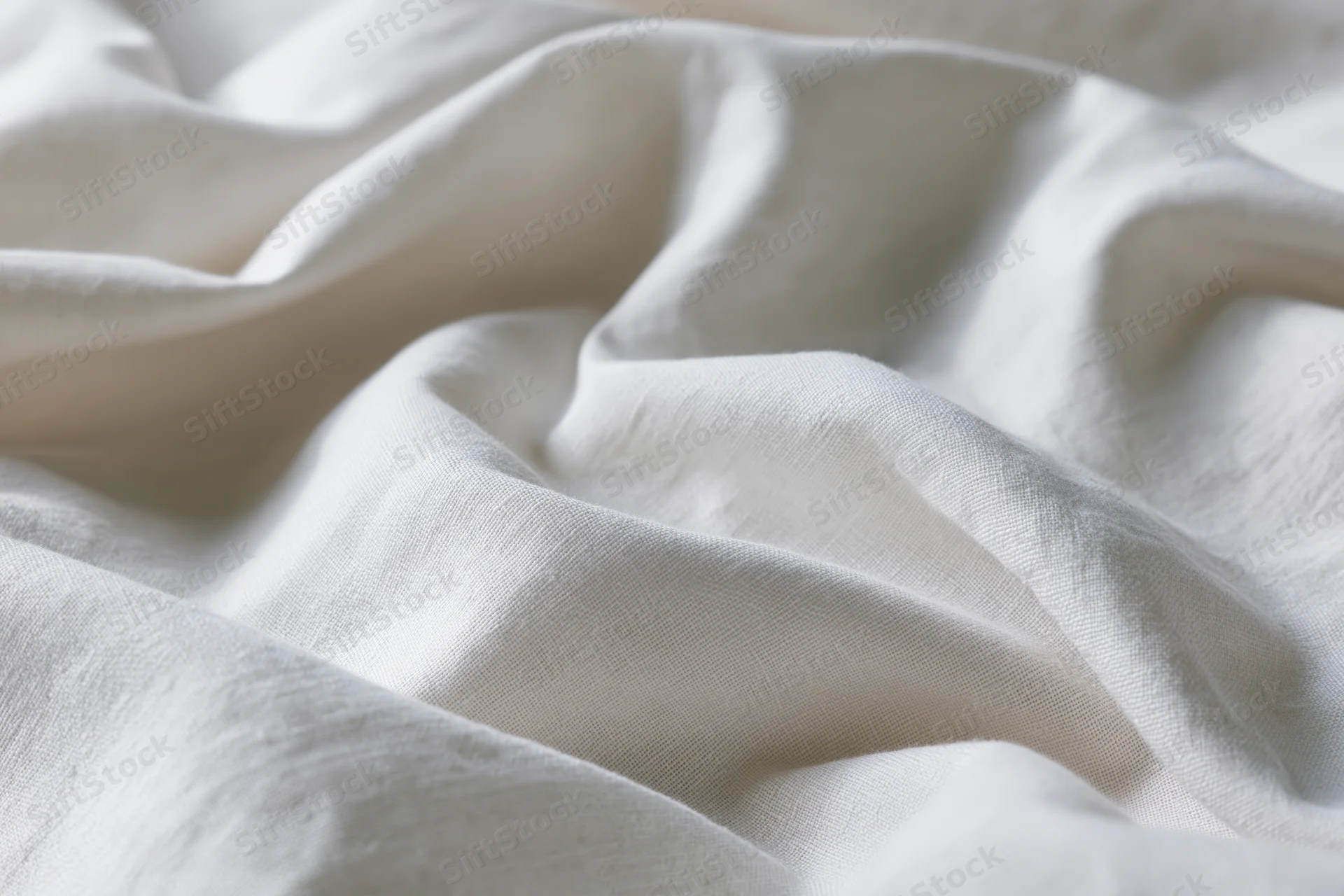 Close-up of crumpled white cotton fabric with soft folds and natural texture filling the frame