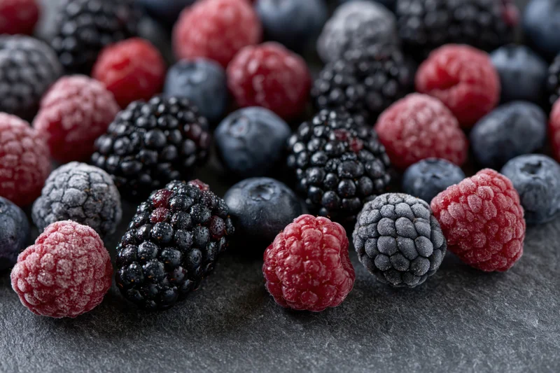 Frozen mixed berries arranged in a closeup flat lay on a dark slate surface