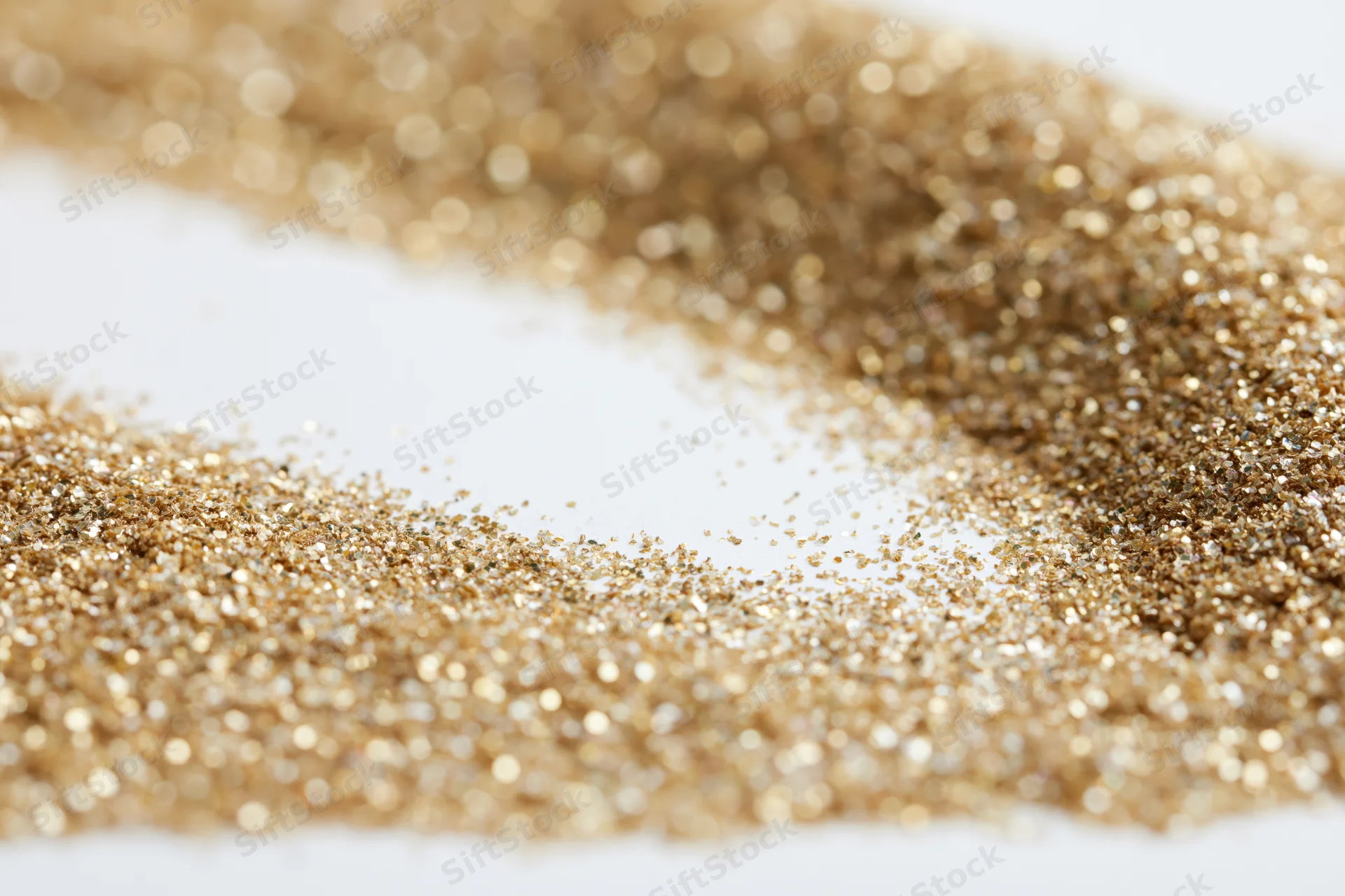 Gold glitter scattered in a circular pattern on white surface