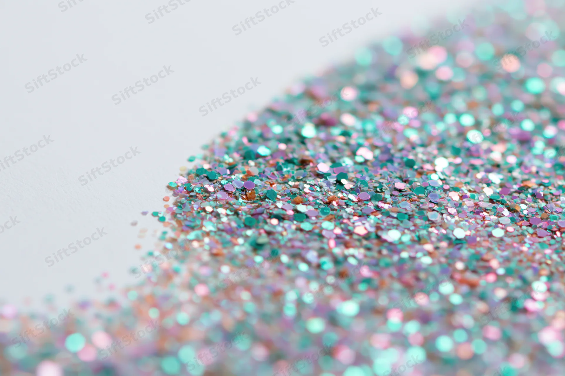 Iridescent glitter scattered densely on a white surface in a flat lay close-up