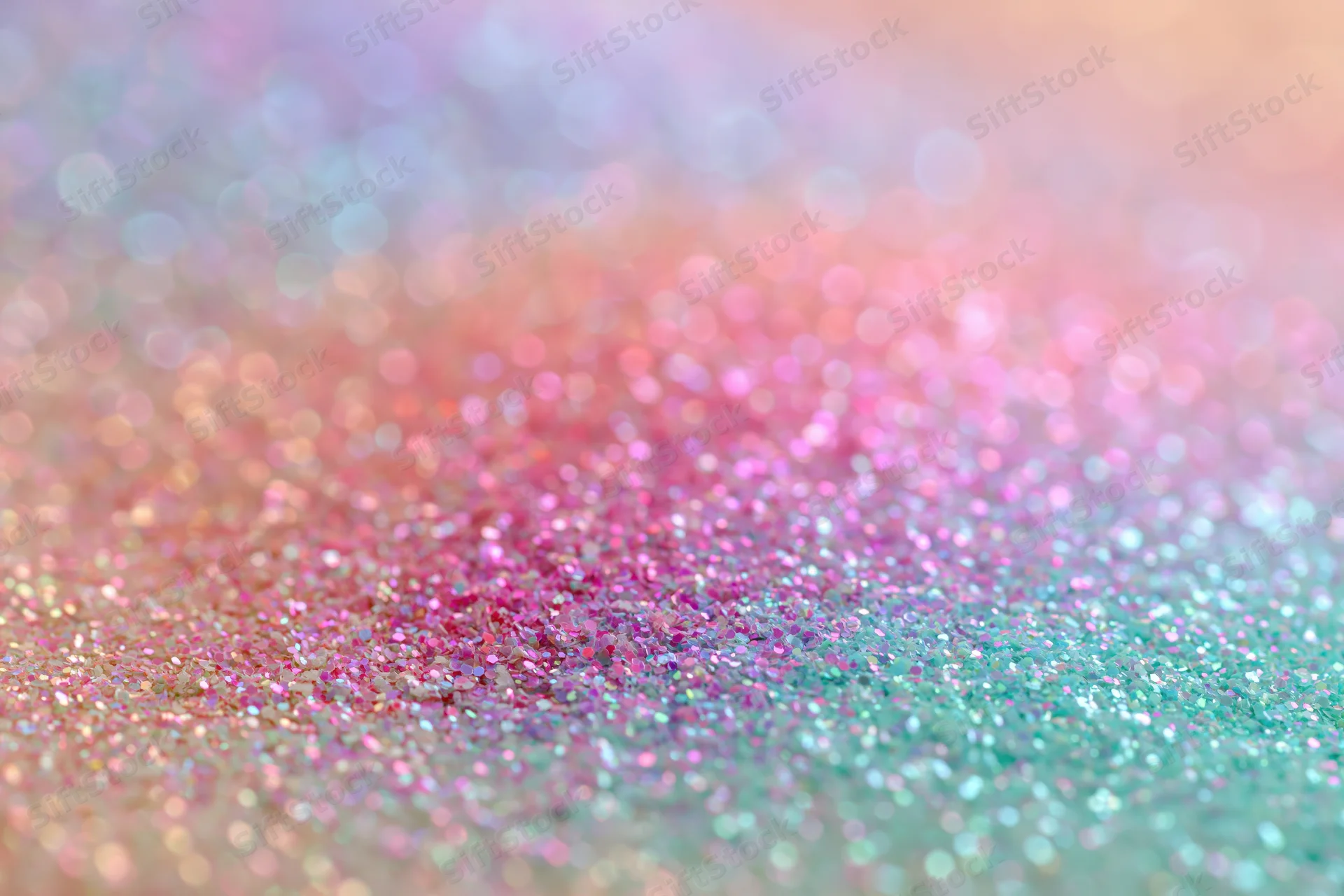 Close-up of iridescent glitter surface with pastel pink and teal sparkle, shallow depth of field