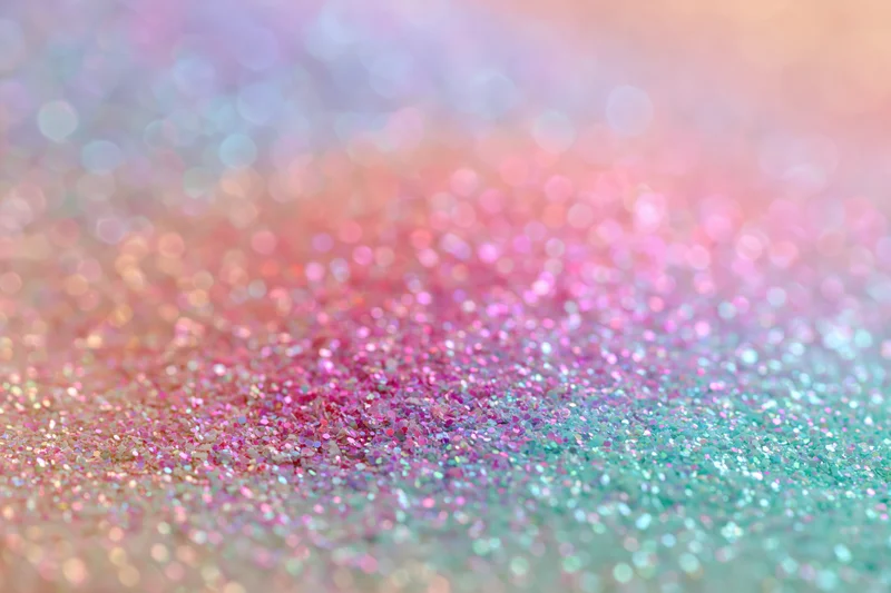 Close-up of iridescent glitter surface with pastel pink and teal sparkle, shallow depth of field