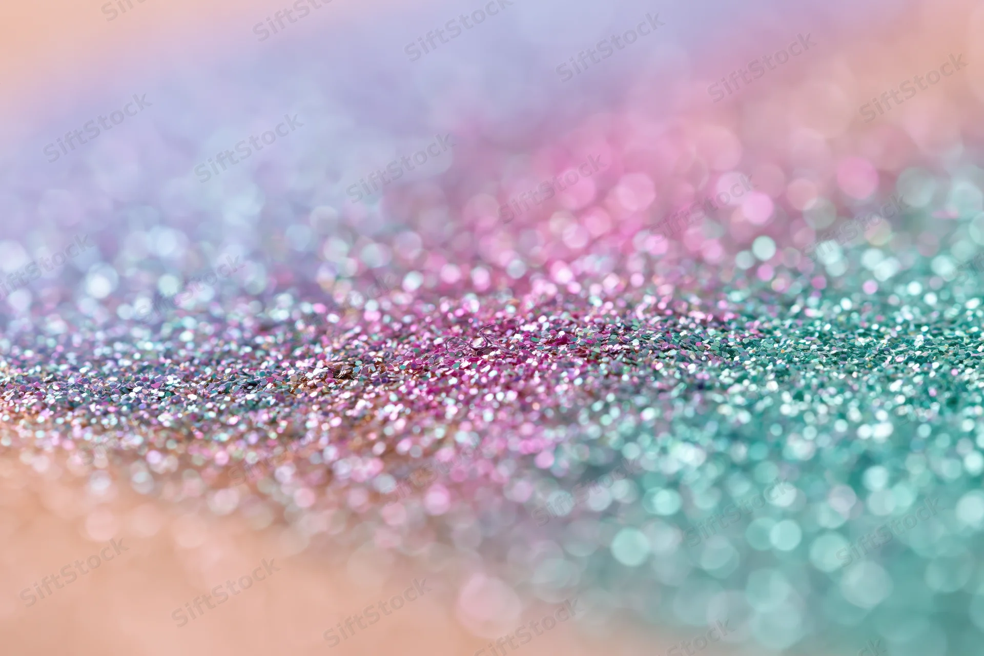 Close-up of iridescent glitter surface with pastel colors and bokeh effect