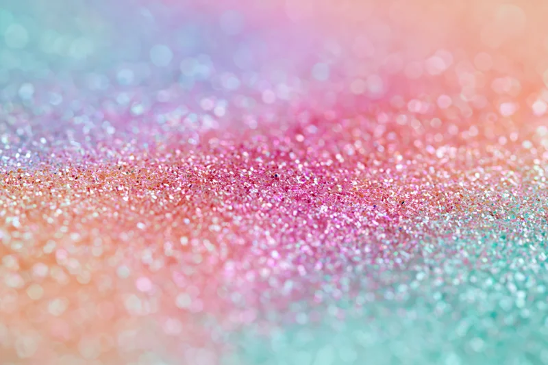 Close-up of iridescent glitter surface with pastel colors and bokeh effect