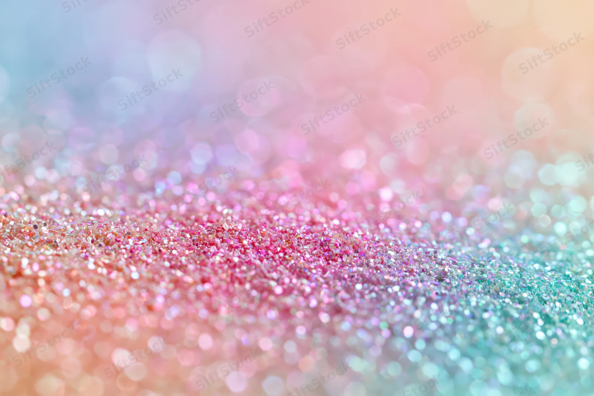 Close-up of iridescent glitter surface with pastel pink and blue hues and bokeh effect