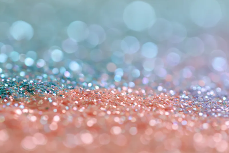Close-up of rainbow glitter surface with bokeh lights and pastel colors