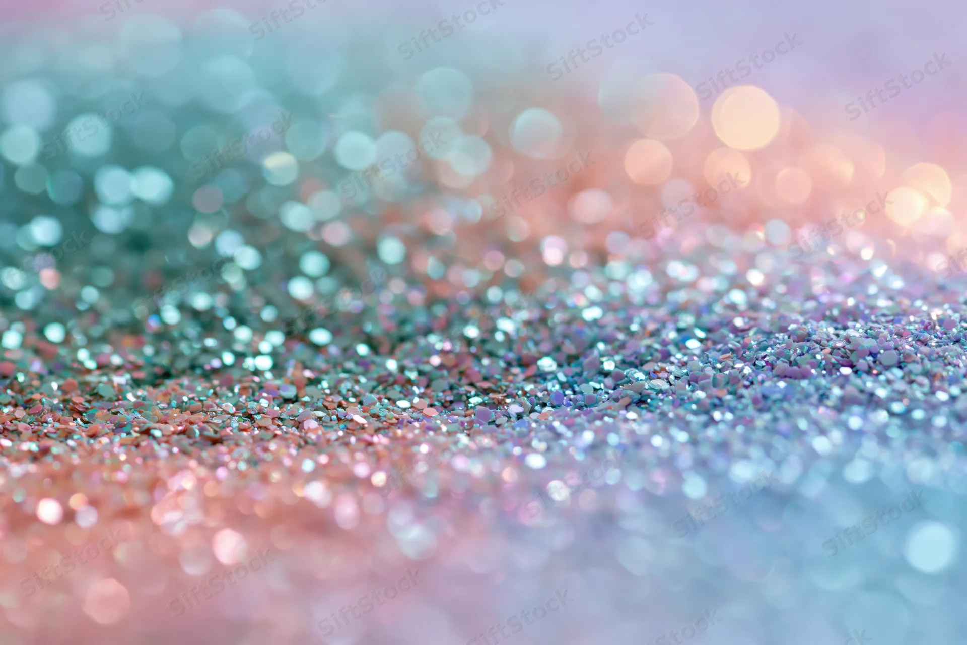 Close-up of iridescent glitter and sequins scattered across a pastel-colored surface with bokeh highlights