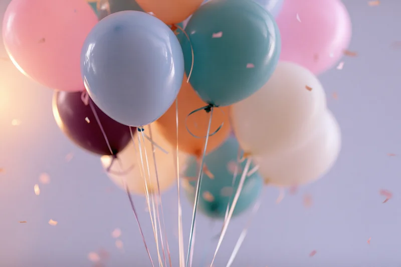 Cluster of colorful latex balloons floating with confetti in the air