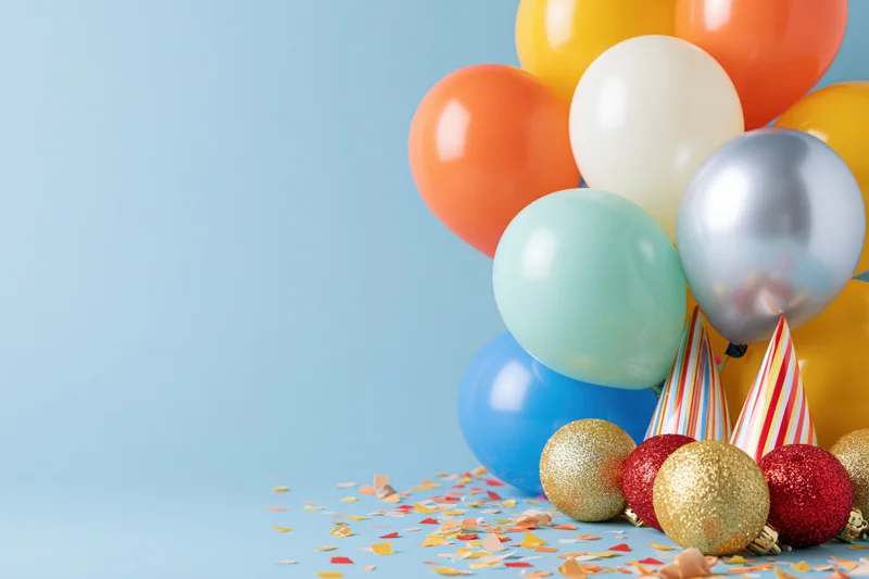 Cluster of colorful party balloons with confetti and ornaments on a blue background