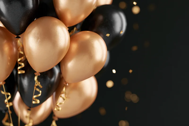Cluster of gold and black balloons with curly ribbons