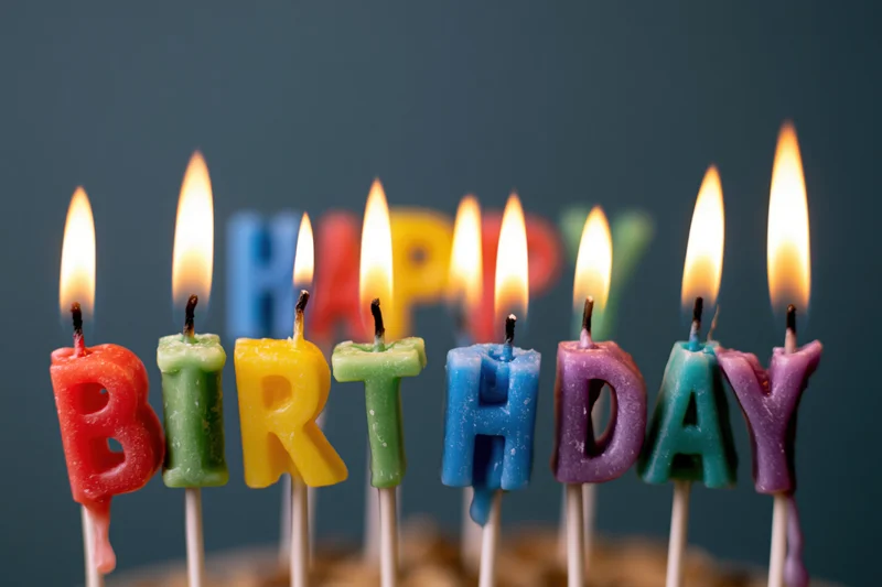 Colorful letter-shaped birthday candles spelling happy birthday on a cake