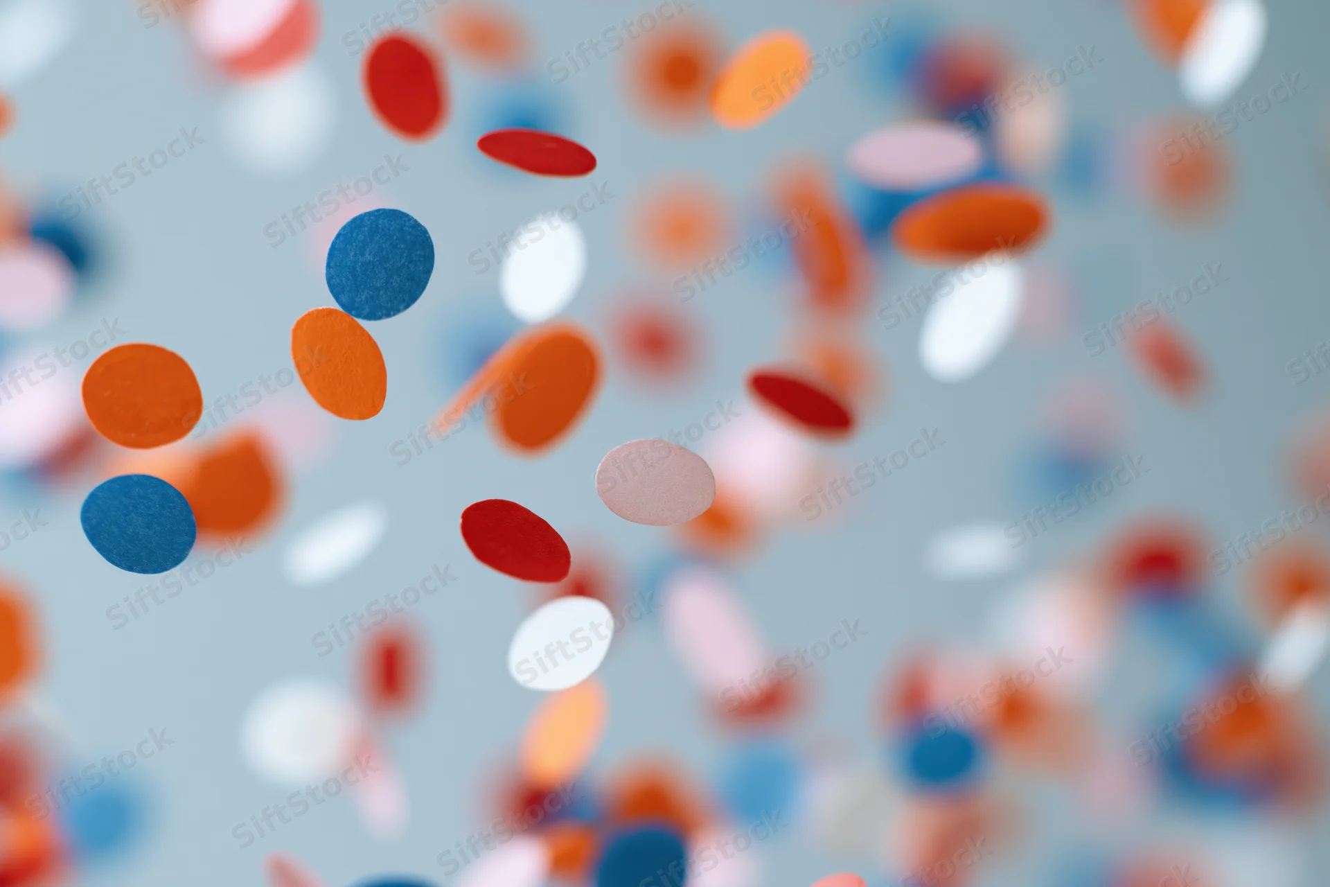 Colorful paper confetti pieces floating midair against a soft light background