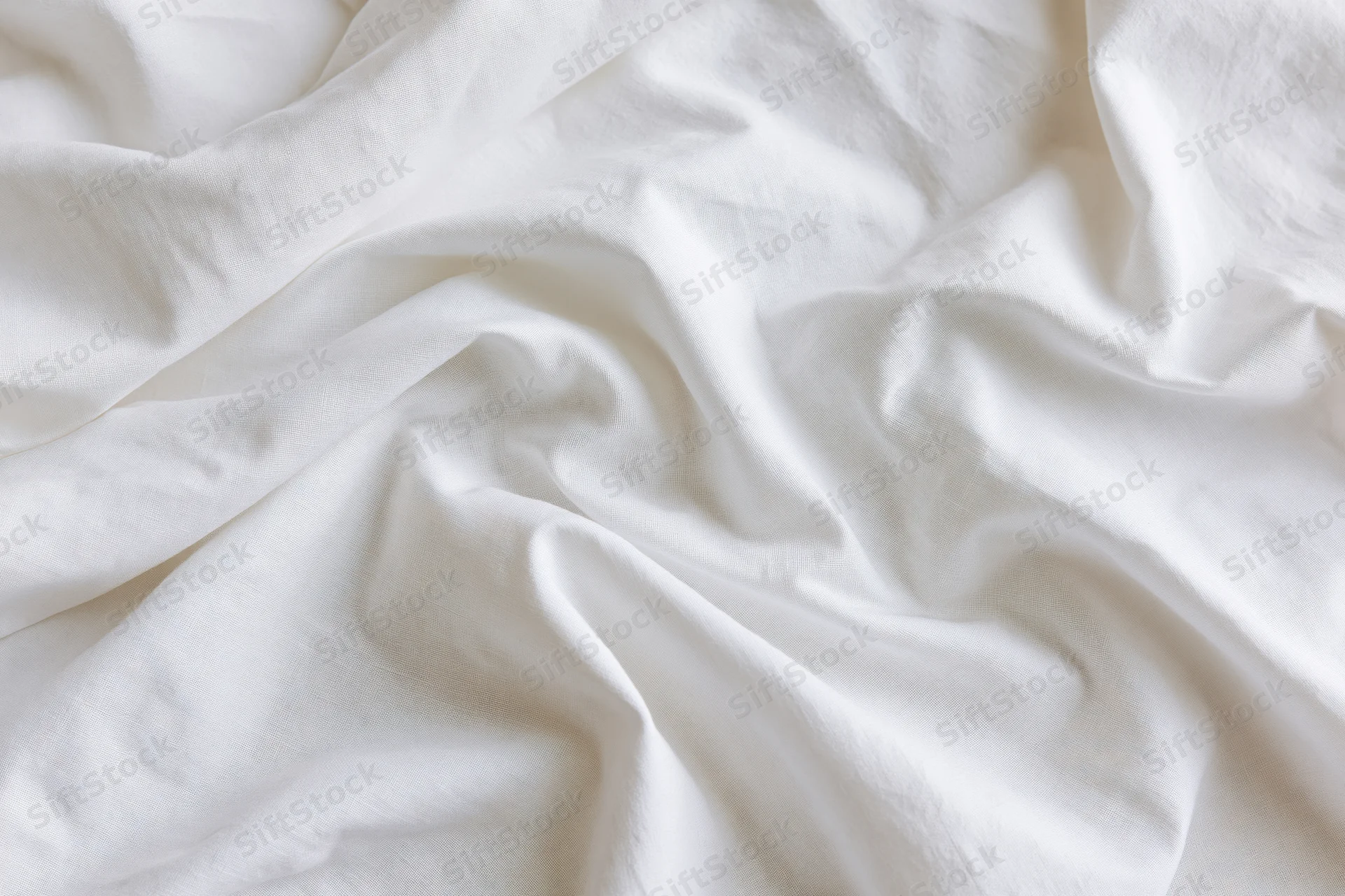 Crumpled white cotton bed sheet filling the frame