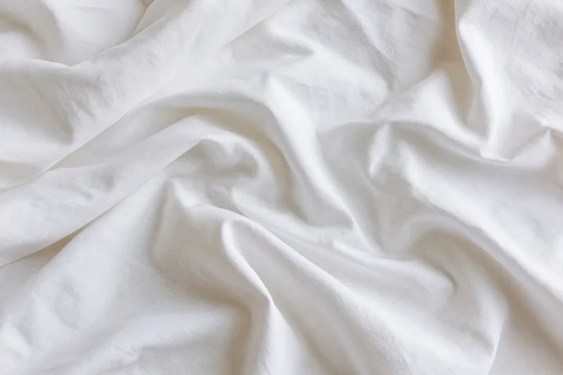 Crumpled white cotton bed sheet filling the frame