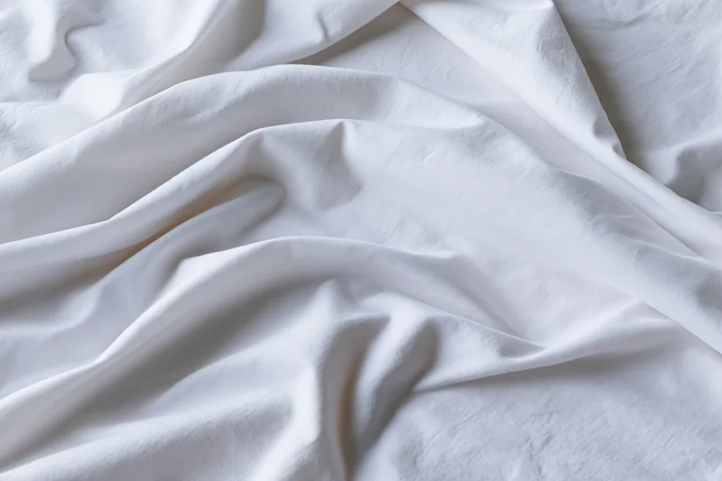 Crumpled white cotton bed sheet filling the frame