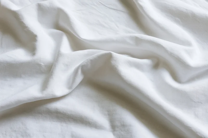 Crumpled white cotton bed sheet filling the frame