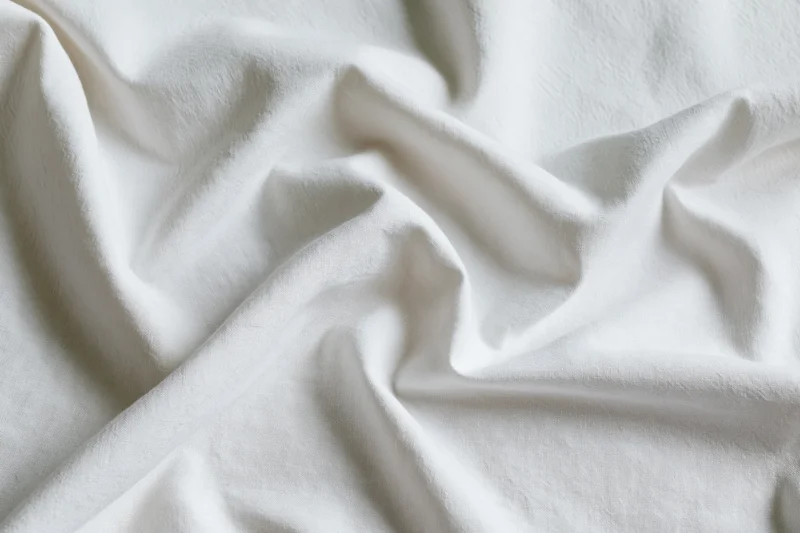 Crumpled white cotton bed sheet filling the frame