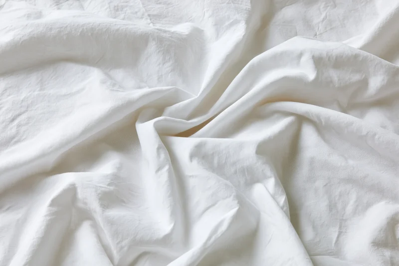 Crumpled white cotton bed sheet filling the frame