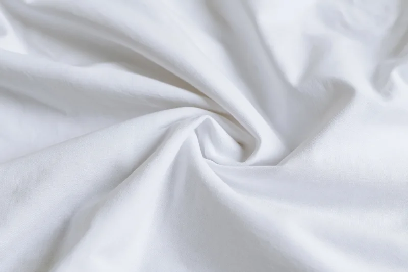 Crumpled white cotton bed sheet filling the frame