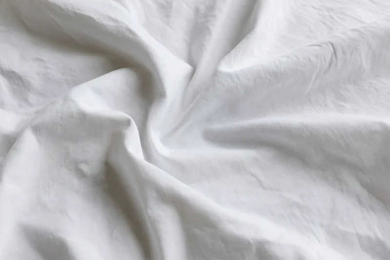 Crumpled white cotton bed sheet filling the frame