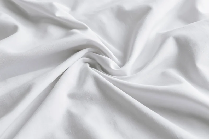 Crumpled white cotton bed sheet filling the frame