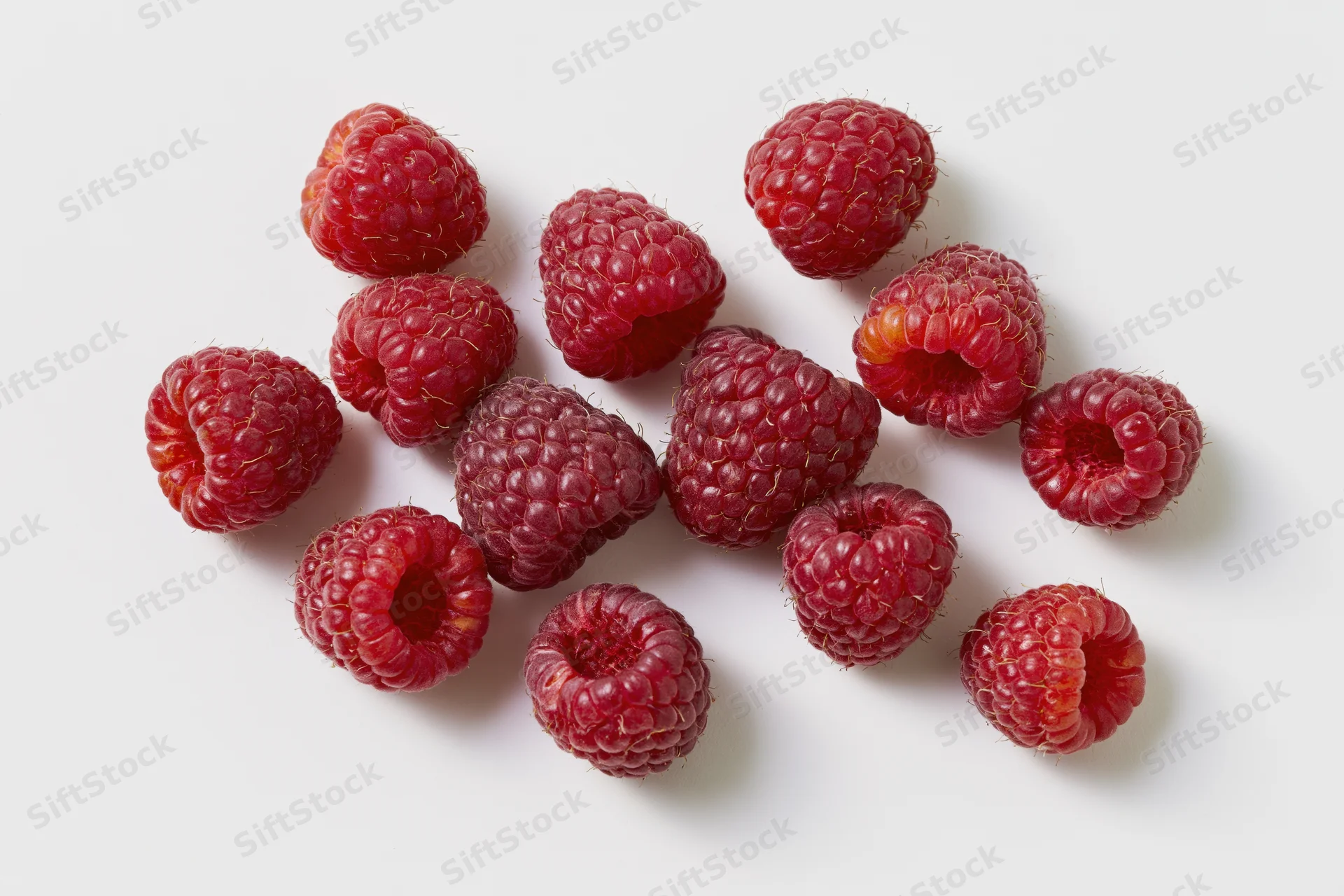 Fresh raspberries scattered on a white surface