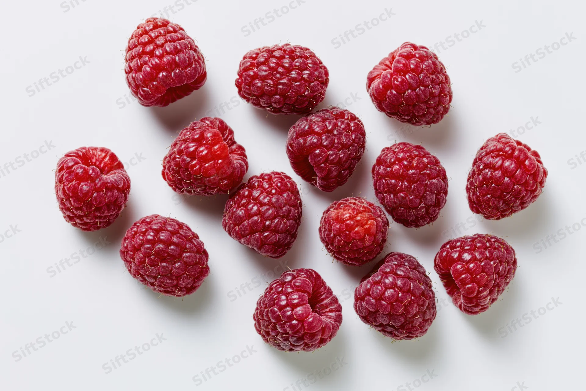 Fresh raspberries scattered on a white surface