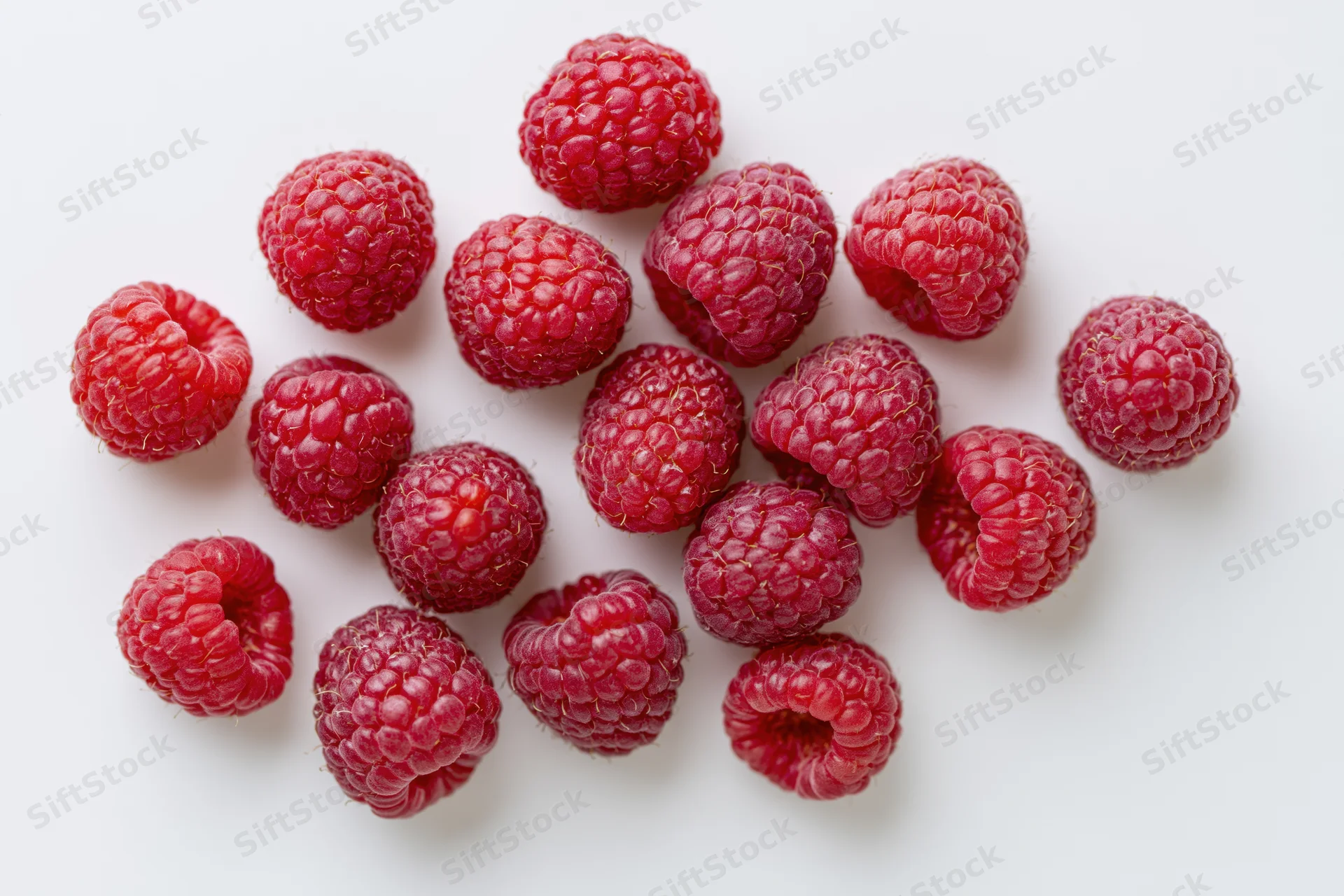 Fresh raspberries scattered on a white surface in a top-down view