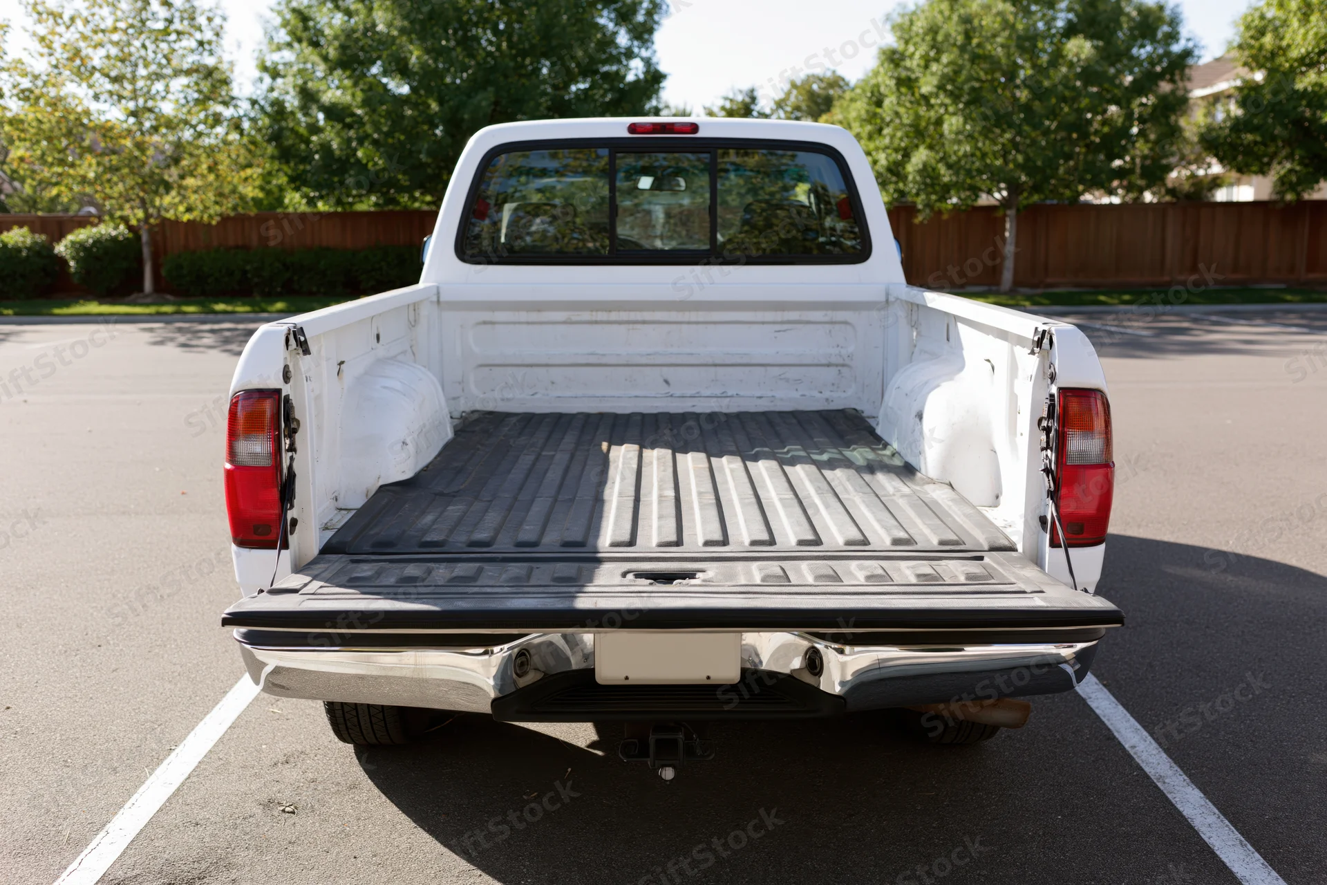 Rear view of white pickup truck with empty bed in parking lot