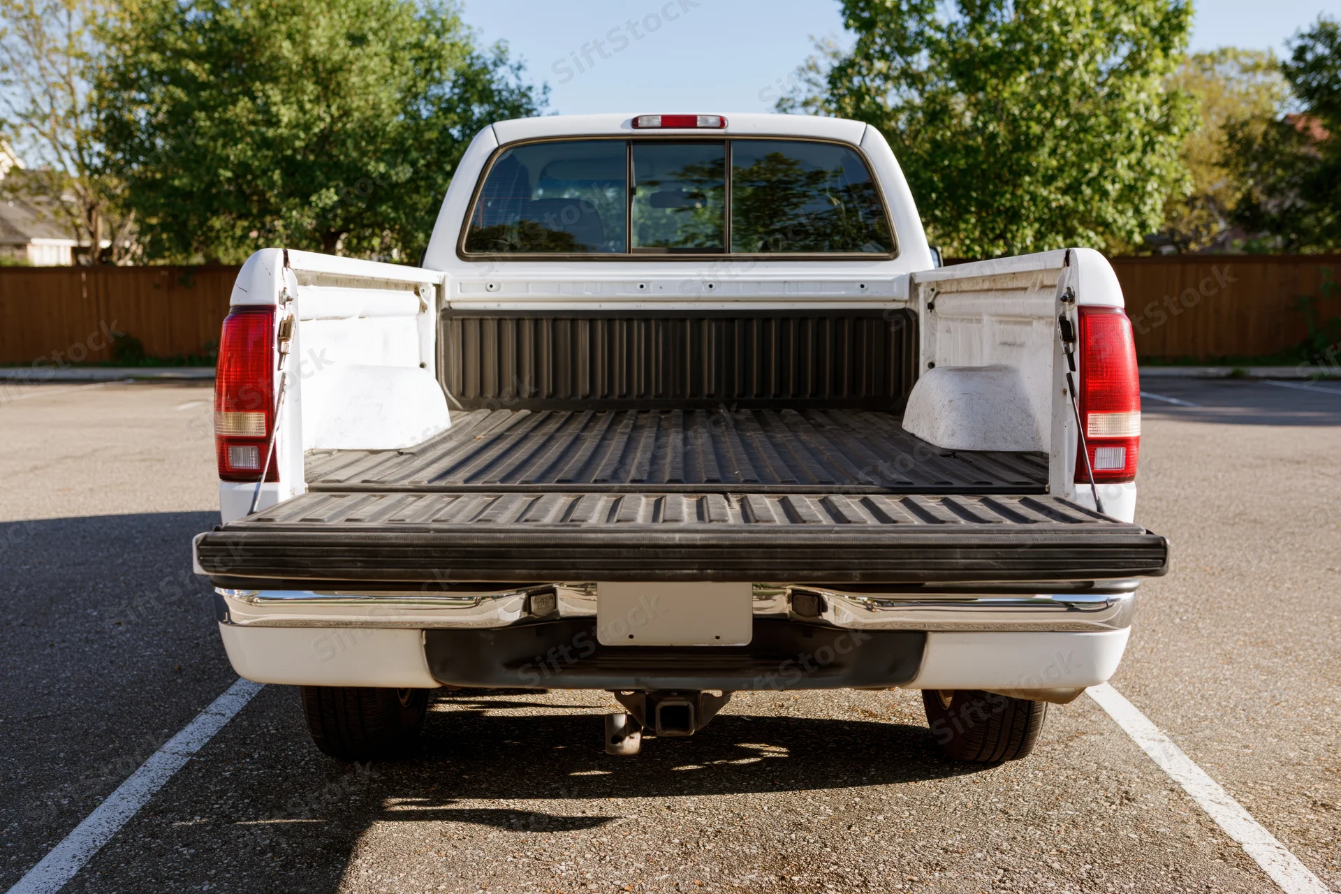 Rear view of white pickup truck with open empty bed in parking lot